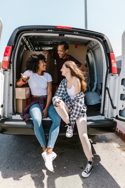 Inside the open rear of a van parked on a paved surface, two workers from Man with Van Thornton Heath are involved in a home relocation process. The van's cargo area is filled with neatly stacked medi